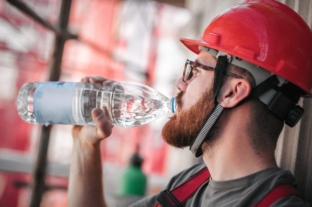 Construction mason worker on scaffolding, resting and staying hydrated