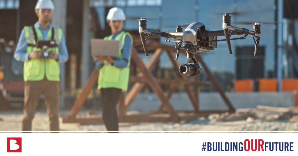 a drone and drone operator with watching it take off with the hashtag #buildingourfuture