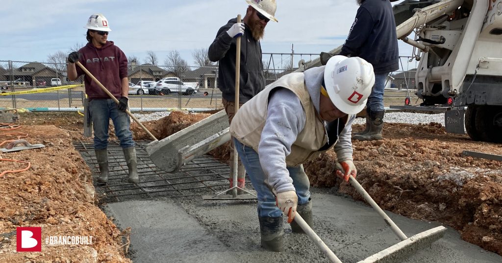 workers standing in concrete as they smooth it out